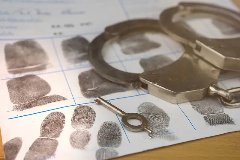 Handcuffs and fingerprint card, symbolizing criminal charges; Lori Beck Law Office provides defense in Denver, CO.