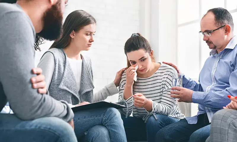 Group offering comfort to a crying woman; Lori Beck Law Office provides compassionate support for families affected by criminal charges or injury in Denver, CO.