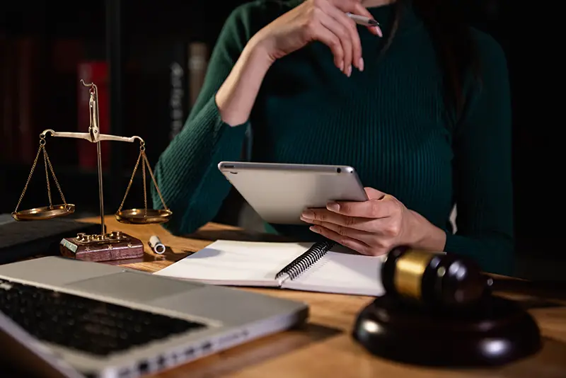 Attorney working with a tablet, gavel, and scales of justice; Lori Beck Law Office provides diligent legal strategy in Denver, CO.