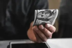 Hand holding a hundred-dollar bill; Lori Beck Law Office offers transparent pricing for legal services in Denver, CO.
