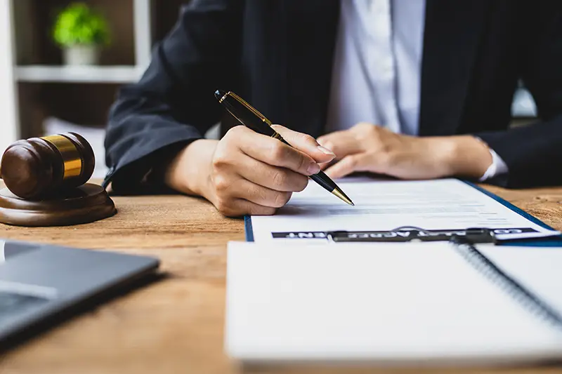 Lawyer signing legal documents with a gavel nearby; Lori Beck Law Office provides contract and settlement expertise in Denver, CO.