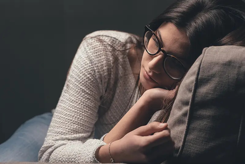 Distressed woman resting her head on a pillow, symbolizing the burden of legal and financial worries; Lori Beck Law Office helps victims in Denver, CO.