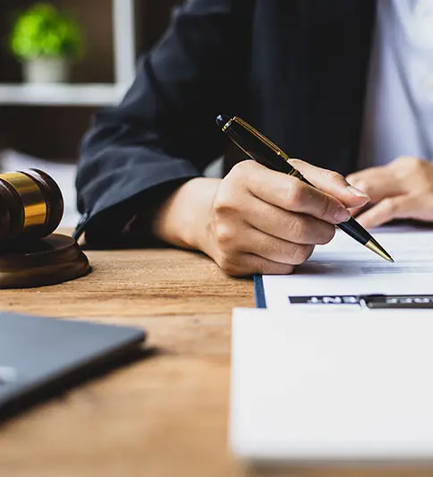 Lawyer signing legal documents with a gavel nearby; Lori Beck Law Office provides contract and settlement expertise in Denver, CO.