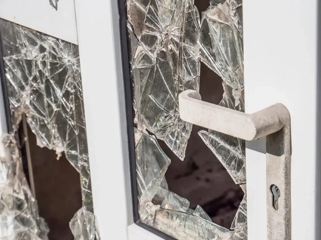 Shattered glass door from property damage, illustrating criminal mischief charges in Colorado.
