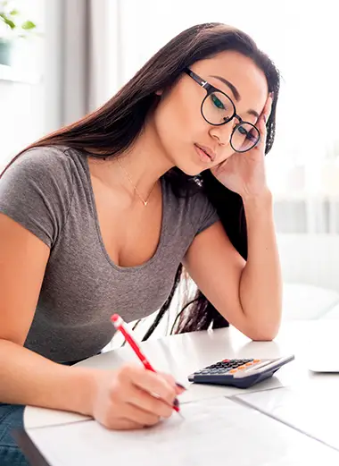 Woman looking at a laptop and calculator, focused on financial or legal paperwork; Lori Beck Law Office helps with billing concerns in Denver, CO.