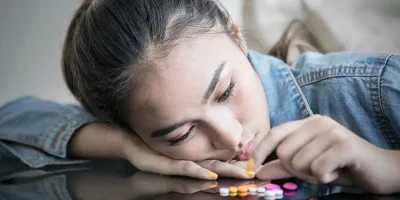 Teenager looking at pills, symbolizing juvenile drug charges; contact Lori Beck Law Office in Denver.