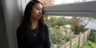 Sad teenage girl looking out a window, symbolizing juvenile legal worries; Lori Beck Law Office provides juvenile defense in Denver, CO.