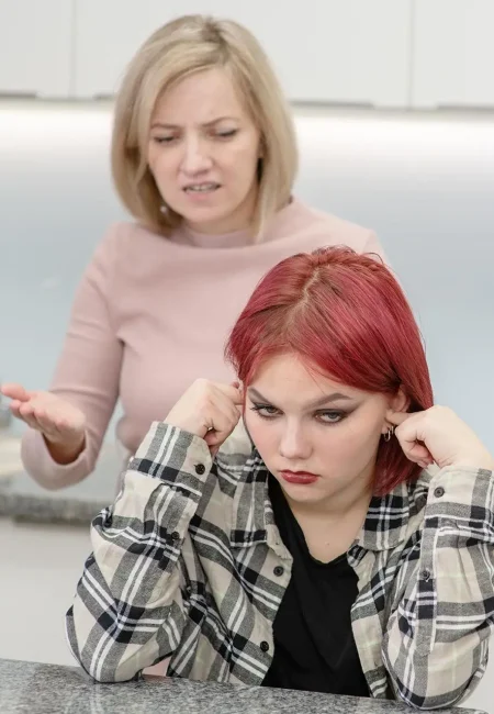 Teenager with red hair ignoring upset parent, symbolizing the challenges of juvenile crime charges and family impact.