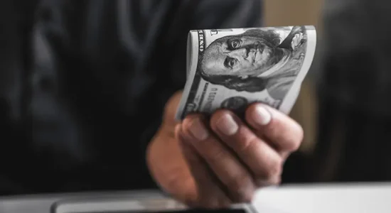 Hand holding a hundred-dollar bill; Lori Beck Law Office offers transparent pricing for legal services in Denver, CO.